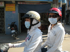 Picture of two girls on motor bike that have their faces covered up in a facemask and helmet