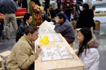 picture of people playing chinese chess against each other, focus is on a man and young girl playing the game