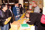 People watching a young man as he is bent over signing a document
