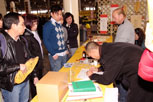 People watching a young man as he is bent over signing a document