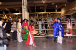 A skit - A girl wearing the traditional vietnamese Ao Dai red dress walks outwards with a basket in hand towards a young man wearing a blue and white costume